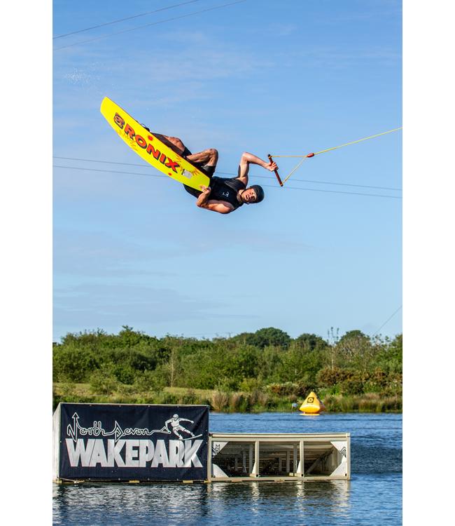 Ronix EPIC Cable Wakeboard - rider inverted above the water at a cable park with the lake behind
