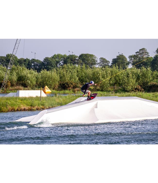 Ronix Kinetik Project Cable Wakeboard - rider taking off from a white kicker at a cable park
