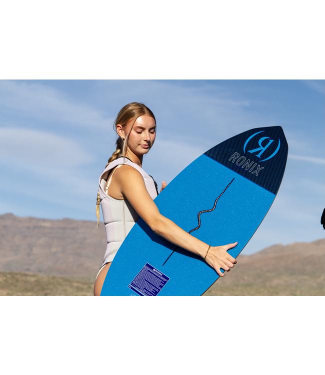 Ronix Moment Womens Skimmer - rider holding the blue board under her arm with hills behind