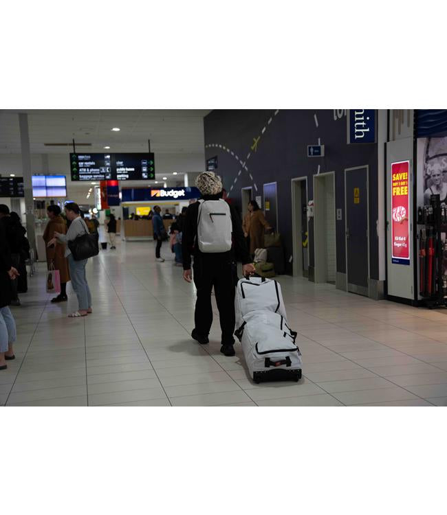 Follow Life Board Travel Bag in Charcoal – lifestyle shot showing the wheeled travel bag being moved through transit