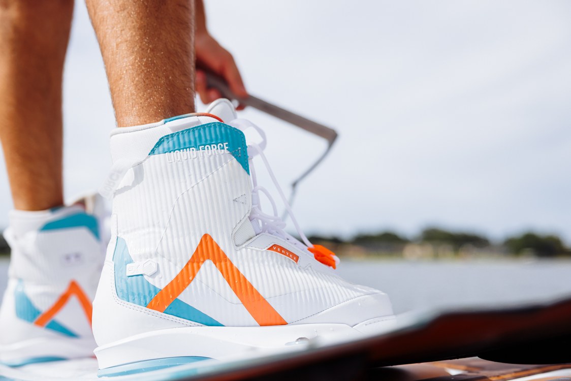 Liquid Force Vertex 6X Wakeboard Boots worn by a rider wakeboarding behind the boat