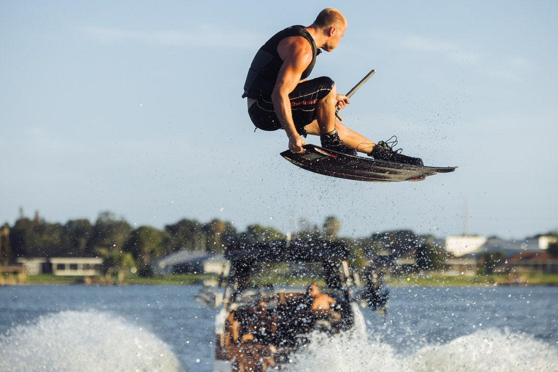 Liquid Force Origin Aero Wakeboard Package on a rider boosting a jump off the wake