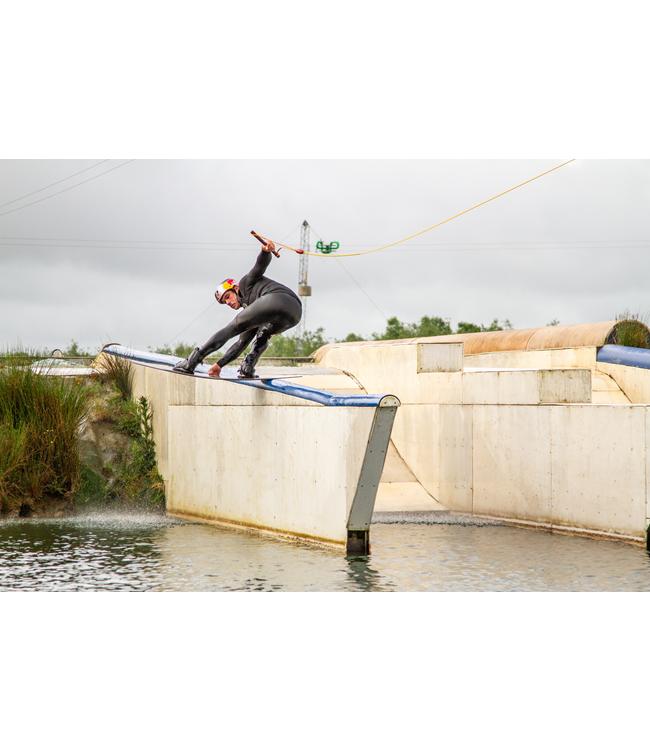 Ronix Pinpoint Cable Wakeboard - rider pressing along a blue rail at a cable park