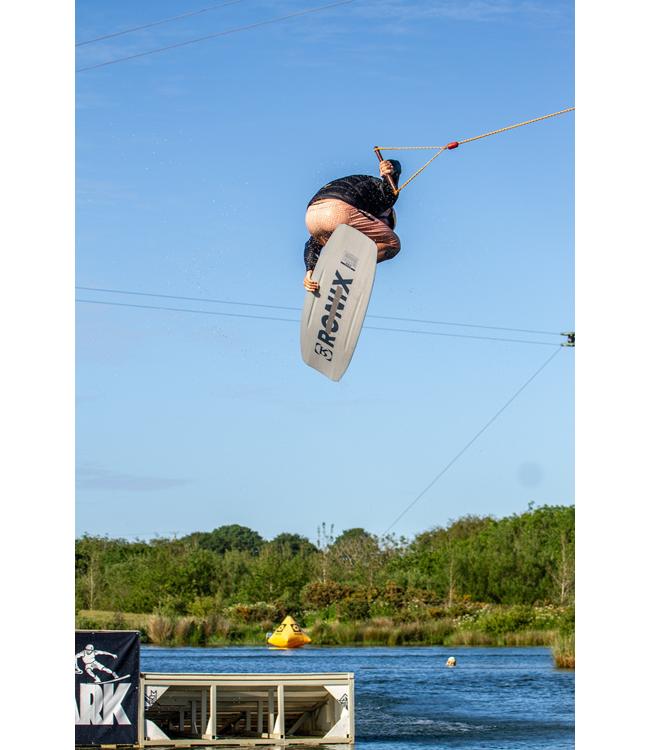 Ronix Pinpoint Cable Wakeboard - rider high in the air above the cable park lake