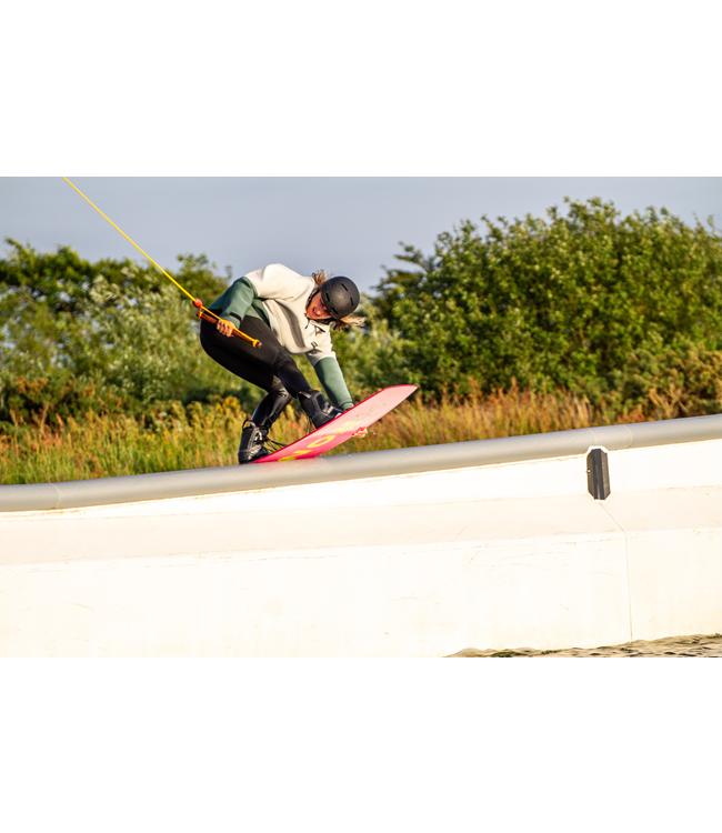 Ronix Spring Break Cable Wakeboard - rider pressing on a white ledge with the pink board underfoot