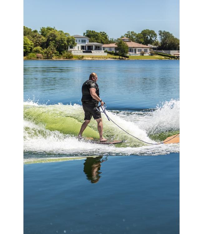 Ronix Wave King Skimmer - rider surfing with the rope in hand and houses on the shoreline