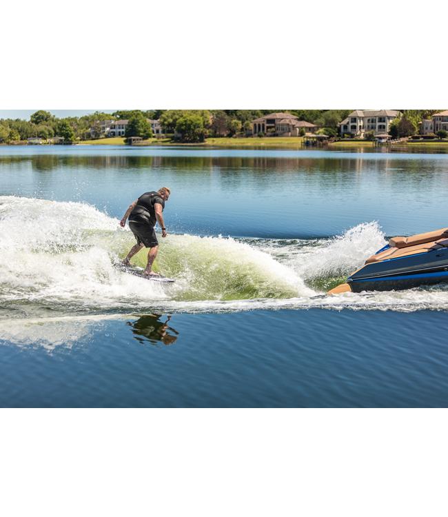 Ronix Wave King Wakesurfer - rider surfing beside the boat with houses on the far bank