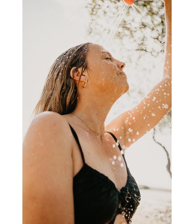 Jetpilot Venture Solar Camp Shower lifestyle shot of rinsing kit at a beach campsite after riding